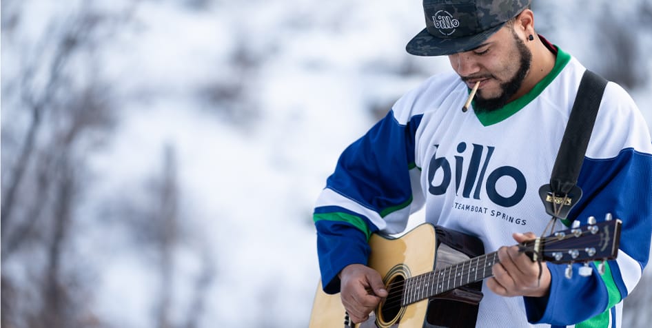 image of a man smoking a joint outside during the winter and playing the guitar