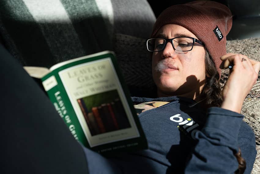 Girl smoking weed while reading a book on couch